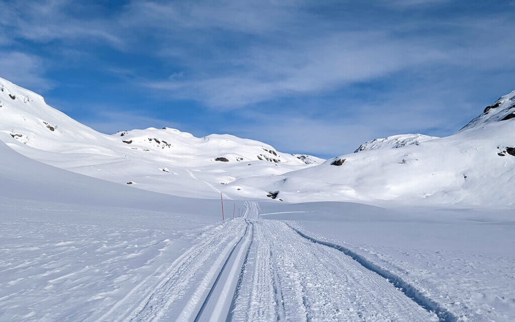 Austerheimsdalen in snow under a blue sky.