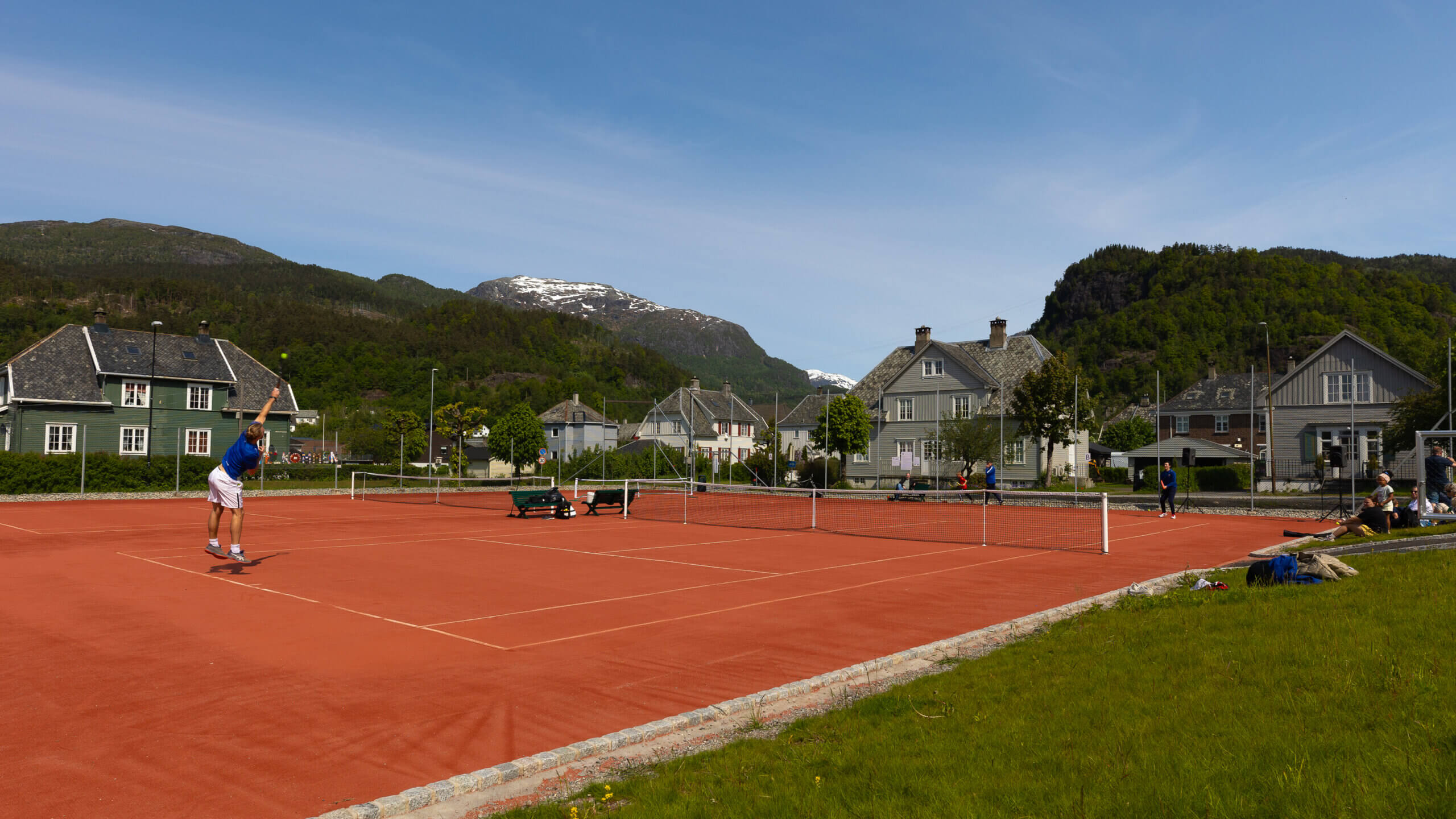 People playing tennis on a tenniscourt in Sauda in summer.